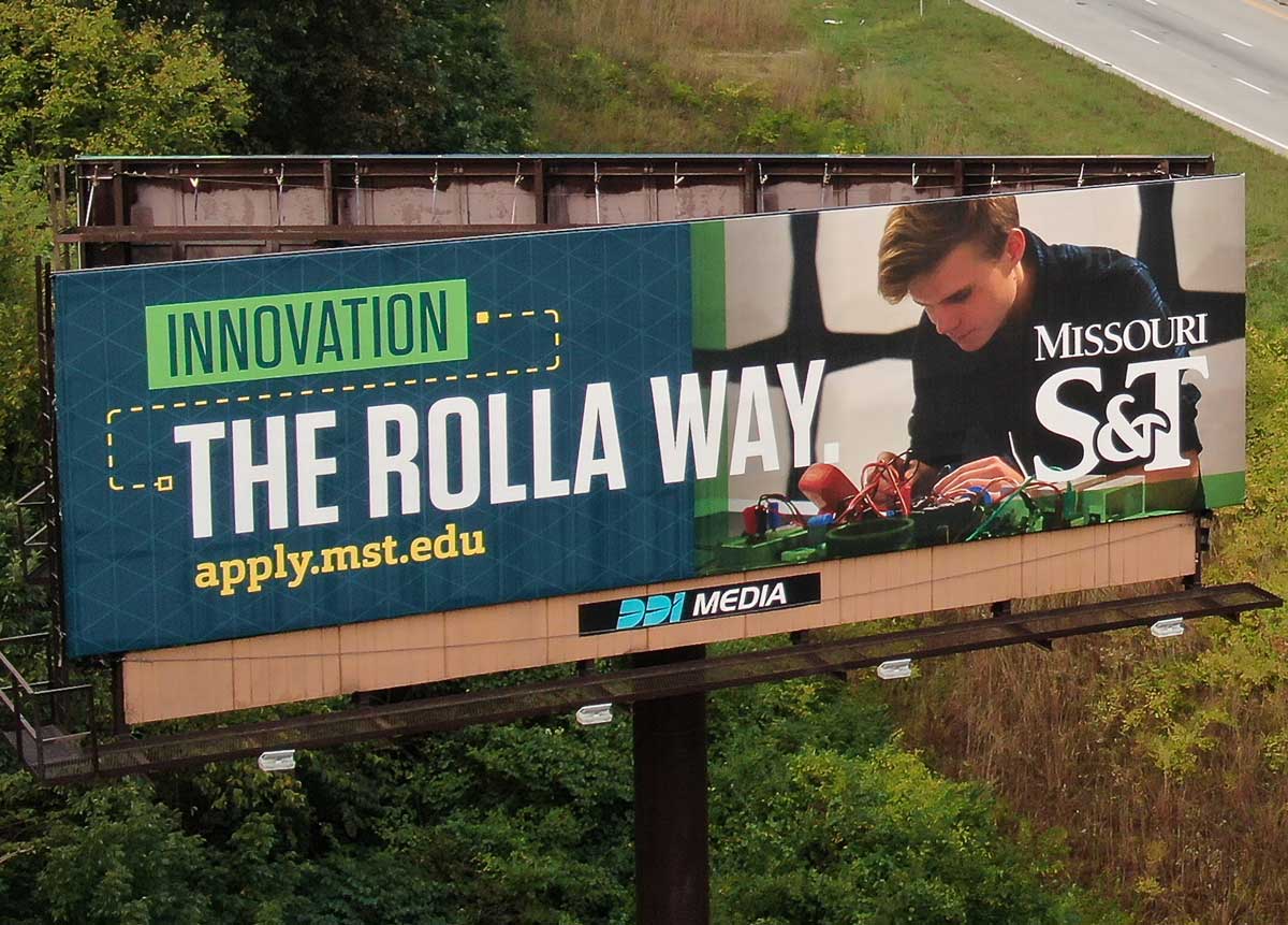 Billboard by the highway with a photo of a male on the right, text on the left reading 