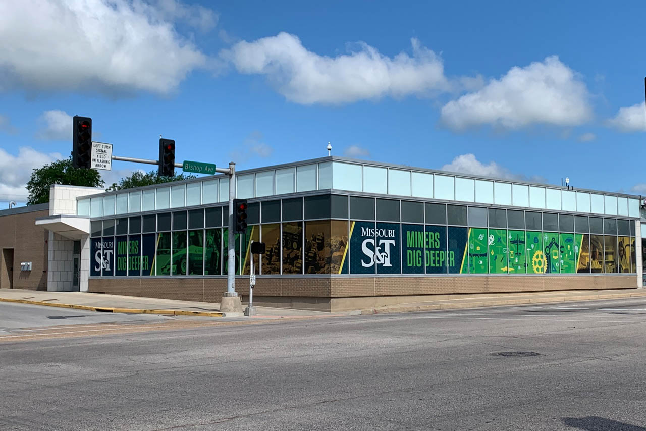 Wide view of building with S&T branded vinyl on windows wrapped around the building